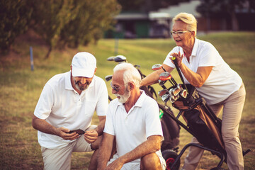 Senior golfers on court. Two men using smart phone.