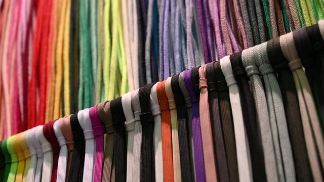 Lots of multicolored textile ropes hang in several rows. Samples of textile products.