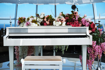 modern musical instrument piano. sound equipment in the center of the living room in the interior. electronic piano decorated with flowers