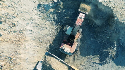 Top view of an excavator digging ore in the quarry