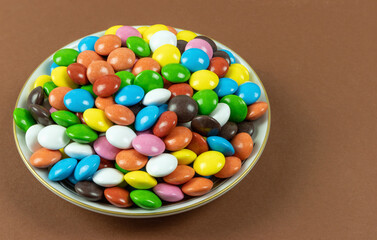 Round milk chocolate balls on a plate on a brown background