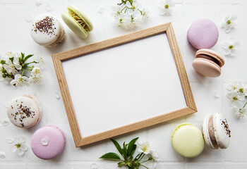 Fototapeta na wymiar Wooden frame mockup with macaroons and spring blossom