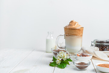 Dalgona coffee, ingredients and flowers on a white background with space to copy.