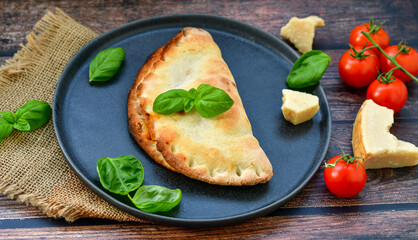 Home made italian calzone vegetarian  pizza with  tomatoes, mozzarella and parmesan cheese and fresh basil 