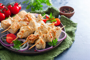 Chicken breast skewers baked in the oven on wooden skewers on a plate, horizontal, copy space