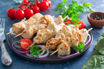 Chicken breast kebab baked in the oven on wooden skewers on a plate, horizontal