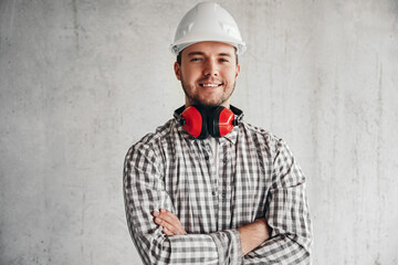 Delighted male builder in hardhat on gray background