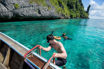 An active man on thai traditional longtail Boat is ready to snorkel and dive, Phi phi Islands, Thailand - obrazy, fototapety, plakaty