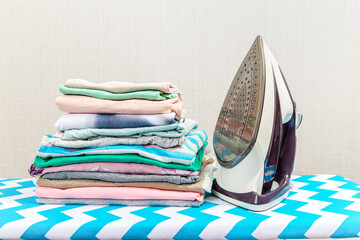 Board with modern iron and shirt at home. Laundry day