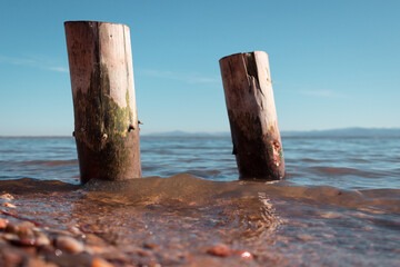 two wooden piles washed by the waters of the lake with the mountains in the background