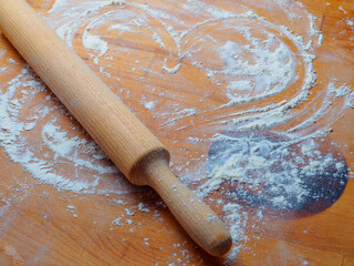 Rolling pin on a wooden table sprinkled with flour and a drawn heart. Making baked goods with love. Copy space.