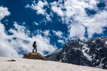 Naklejka na ściany i meble A lone hiker looks at the view of the Himalayas on the Beas Kund trek in northern India