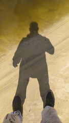 Shadow of a man on the river bank. Vertical photo.