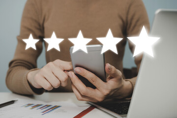 Excellent. woman hand working on mobile phone with five star rating button on visual screen to...