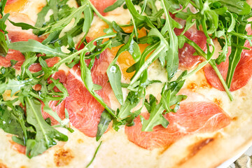 Italian pizza with carpaccio meat from wood-burning stove. lunch in an Italian restaurant. Table near to a large window.