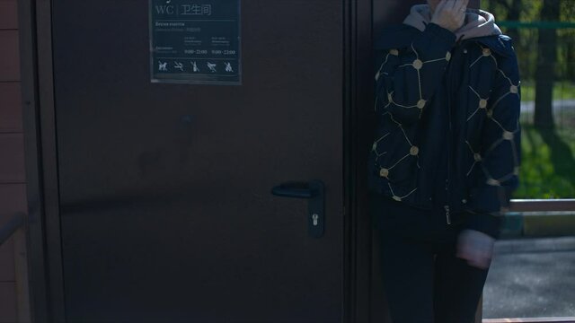 Young woman doesn't like smell in public toilet in town park. What a mess