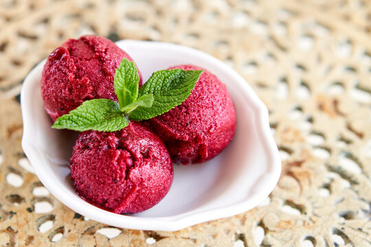 Italian gelateria. Berry ice cream with mint leaf. three balls in a white bowl on a vintage table. sorbet
