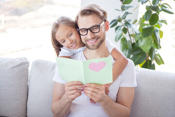 Photo of pretty shiny father daughter dressed casual clothes sitting couch reading handmade postcard indoors house apartment © deagreez