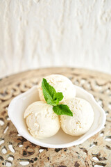 Italian gelateria. Vanilla ice cream with mint leaf. three balls in a white bowl on a vintage table.