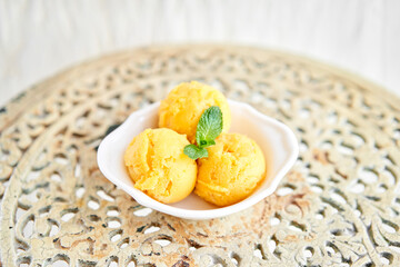 Mango ice cream with mint leaf. three balls in a white bowl on a vintage table. sorbet - obrazy, fototapety, plakaty