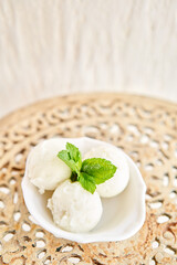 Linon ice cream with mint leaf. three balls in a white bowl on a vintage table. sorbet