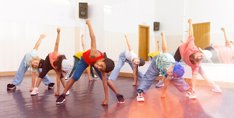 Group of children in casual clothes training hip-hop in class, learning modern dance movements