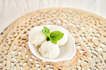 Linon ice cream with mint leaf. three balls in a white bowl on a vintage table. sorbet