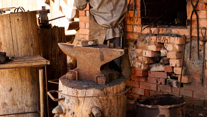 Plakat A blacksmith in an authentic workshop. Blacksmithing in the village. Focus on the metal anvil