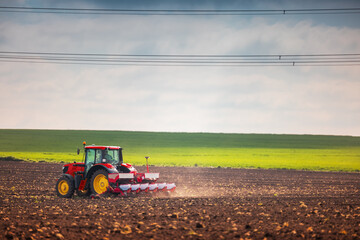 Obraz premium Farmer with tractor seeding crops at field
