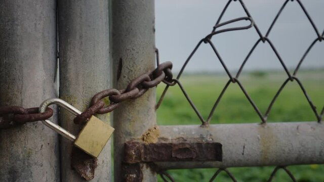 Close up old padlock and rusty chain on fence gate, Locked metal door of entrance, Close steel grate and lock,
Concept lockdown and safety, Handheld show motion shot, Shallow depth of field.