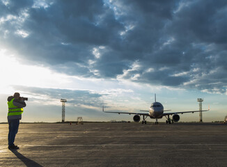 Silhouette of a spotter photographer with a camera and a telephoto lens, taking photos of an...