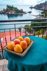Vertical image of a terrace with mango fruits on the table, Splendid view of IsolaBella , Sicily 