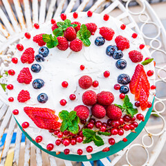 High angle view of creamy cake decorated with soft berries on the top 