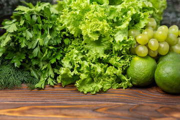 Green vegetables frame. Fresh green vegetables with space for text. Fitness food cooking on wooden background, copy space. Mix of fresh green salad leaves with arugula, lettuce, spinach and beet