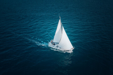 Regatta sailing ship yachts with white sails at opened sea. Aerial view of sailboat in windy...