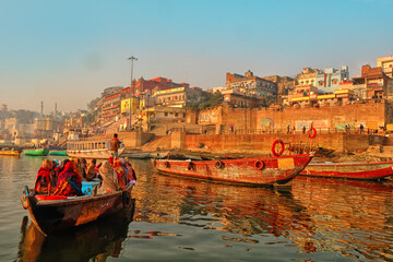 Obraz premium India, Varanasi Ganges river ghat with ancient city architecture as viewed from a boat on the river at sunset.