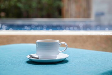 The coffee mug placed on the table has a blue tablecloth