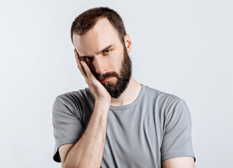 Portrait of handsome young man frowning while holding hands near head on white background with space for advertising mock up