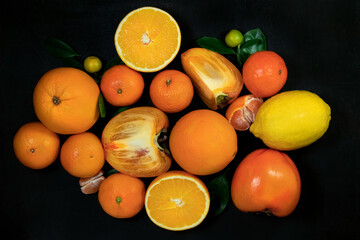 Orange fruits with leaves on a black background. Top view.