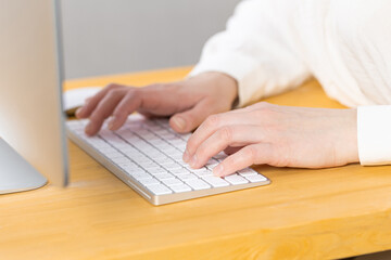 Woman office worker typing on white keyboard