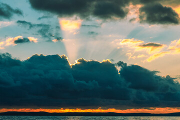 Beautiful sunset at the sea. Rays of light break through from behind the clouds. Natural background