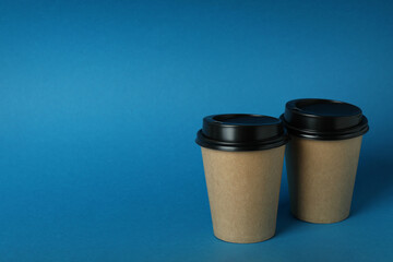 Blank paper cups on blue background, space for text