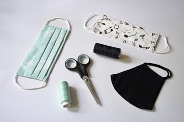 Three type of DIY fabric cotton face mask with scissors and spool of tread on white background