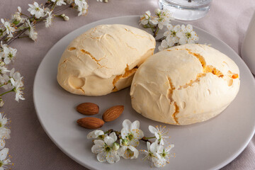 Big meringue cookies on a plate with almonds and white flowers