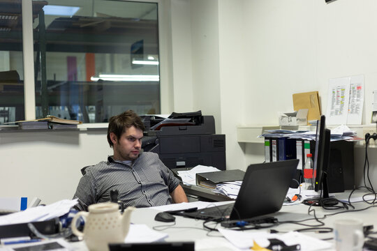 Ersch&ouml;pfter Mitarbeiter sitz abends vor seinem Laptop im B&uuml;ro und macht &Uuml;berstunden