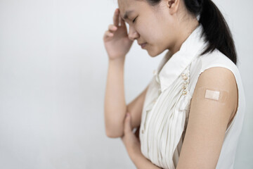 Tired asian lady girl with a fever,headache,fatigue,dizziness,allergic reactions to the COVID-19 vaccine after injection,side effects of receiving medicine to prevent Coronavirus,vaccination concept - obrazy, fototapety, plakaty