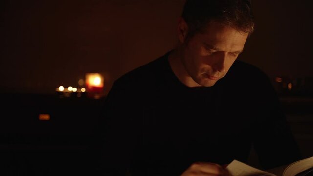 Handsome man reading book at night.