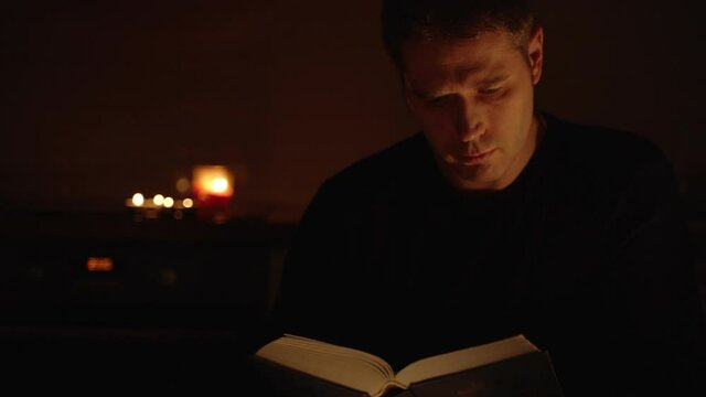 Handsome man reading book at night.