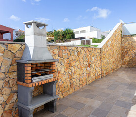 Simple and clean outdoors space with a barbecue to grill some meat. In the background there are...