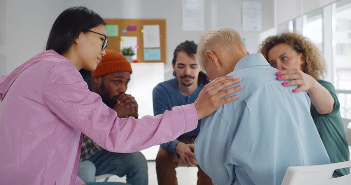 Diverse people supporting senior crying woman at therapy session